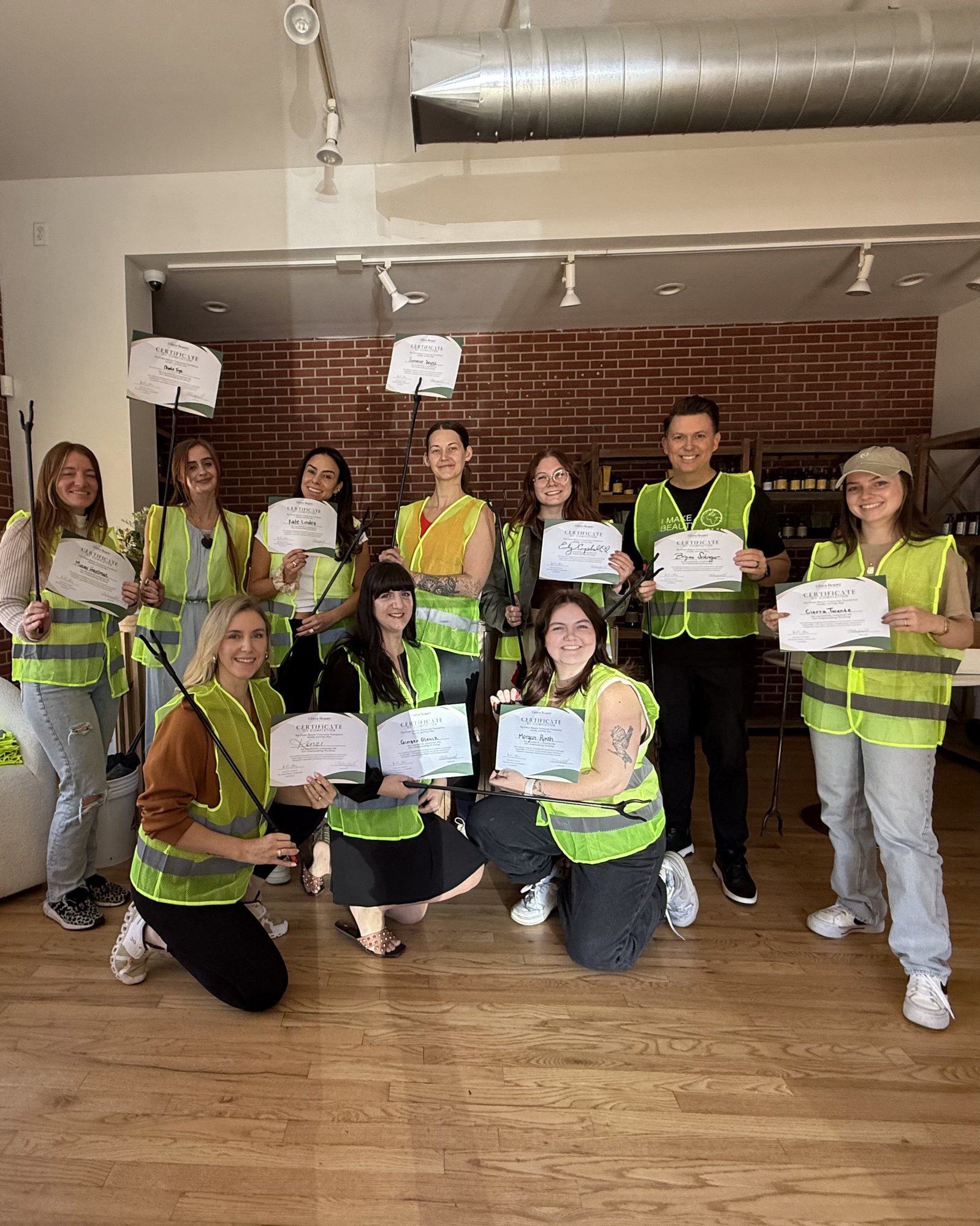 Mazey Heydman and community members holding certificates after a TRU Salon cleanup activity